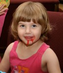 S eating frosting while decorating a cake.